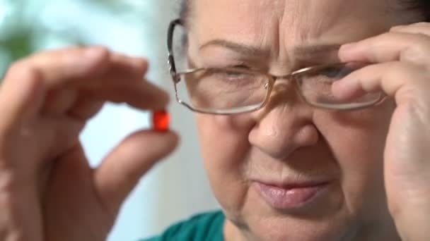 Closeup of a senior woman with red pill. — Stock Video