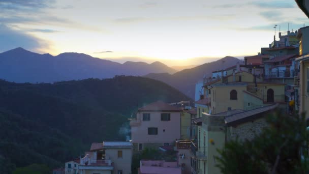 Den stigande solen lyser upp taken i en medeltida stad i bergen. — Stockvideo