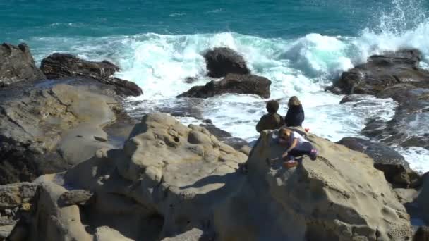 Menschen genießen Sonne und Wellen an den Klippen der Küste — Stockvideo