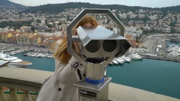 Mujer joven mirando a través de los prismáticos estacionarios en una vista panorámica en Niza, Francia — Vídeos de Stock