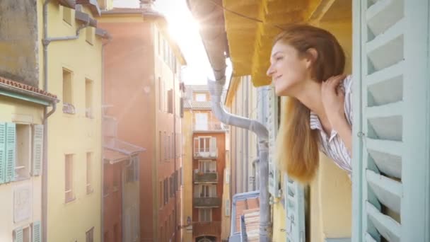 Mladá žena do středověké ulice, usmíval se a mával rukou při pohledu z okna