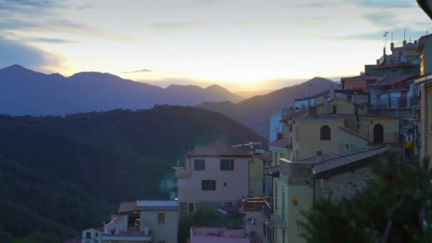 Den stigande solen lyser upp taken i en medeltida stad i bergen. — Stockvideo