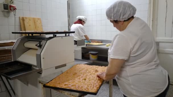 Traditionele Italiaanse bakkerij. Een vrouwelijke Bakker snijdt een grote taart in stukken — Stockvideo