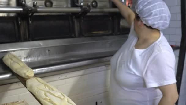 Panadería tradicional italiana. La mujer Baker pone el pan en el horno para hornear mediante el uso de una tabla larga especial . — Vídeos de Stock