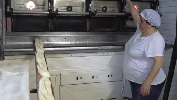 Panadería tradicional italiana. La mujer Baker pone el pan en el horno para hornear mediante el uso de una tabla larga especial — Vídeos de Stock