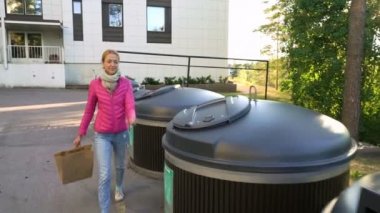 Farklı çöp kutularına farklı çöp koyan genç bir kadın.