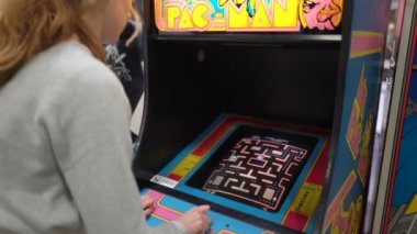 80 'lerin eski slot makinelerinde Pacman klasik oyunu oynayan genç bir kadın.