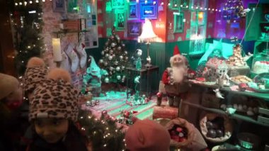Çocuklar ve yetişkinler Noel tatilinin vitrinlerine bakıyorlar.