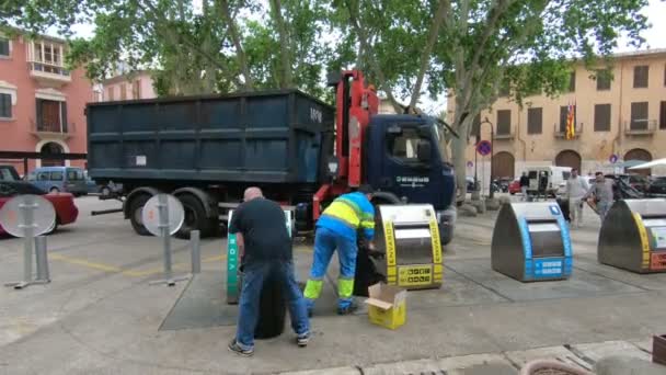 Szeméttisztítók egy nagy teherautó gyűjteni szemetet konténerek a város központjában — Stock videók