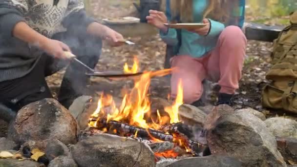 Kvinnliga vänner lagar traditionella pannkakor över öppen eld i lägret utomhus under en vandring — Stockvideo