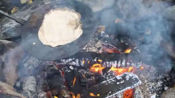 Amigos cocinando panqueques tradicionales sobre una chimenea abierta en el campamento al aire libre durante una caminata — Vídeo de stock