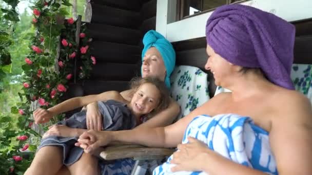 Trzy miłośniczki sauny cieszą się świeżym powietrzem na werandzie tradycyjnej sauny fińskiej — Wideo stockowe