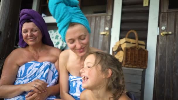 Tres mujeres amantes de la sauna disfrutando del aire fresco en el porche de una sauna tradicional finlandesa — Vídeo de stock