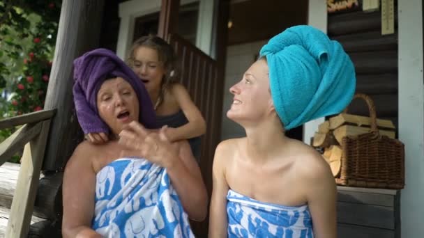 Tre amanti della sauna femminile che si godono l'aria fresca sotto il portico di una sauna finlandese tradizionale — Video Stock