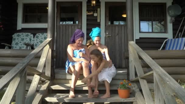 Three female sauna lovers enjoying fresh air on the porch of a traditional Finnish sauna — Stock Video