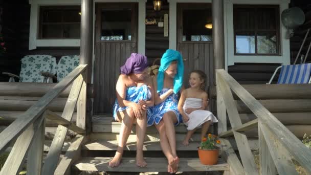 Tres mujeres amantes de la sauna disfrutando del aire fresco en el porche de una sauna tradicional finlandesa — Vídeo de stock