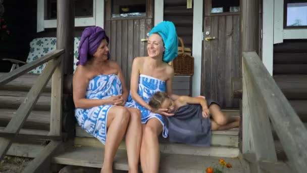 Három női szauna szerelmesei élvezi a friss levegőt a tornácon egy hagyományos finn szauna — Stock videók