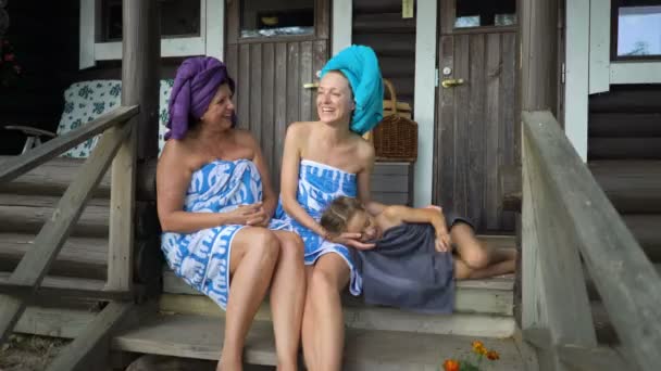 Tres mujeres amantes de la sauna disfrutando del aire fresco en el porche de una sauna tradicional finlandesa — Vídeos de Stock