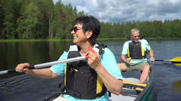 Parejas maduras haciendo piragüismo en un lago forestal en Finlandia . — Vídeos de Stock