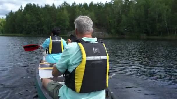 Parejas maduras haciendo piragüismo en un lago forestal en Finlandia . — Vídeo de stock