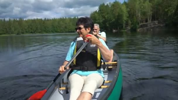 핀란드의 숲 속에 있는 한 호수에서 카누를 타는 성숙 한 부부. — 비디오