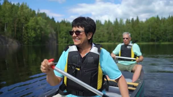 Parejas maduras haciendo piragüismo en un lago forestal en Finlandia . — Vídeos de Stock