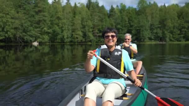핀란드의 숲 속에 있는 한 호수에서 카누를 타는 성숙 한 부부. — 비디오