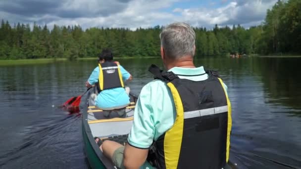 Parejas maduras haciendo piragüismo en un lago forestal en Finlandia . — Vídeos de Stock