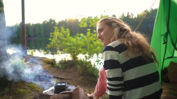 Une jeune femme dans la tente au bord d'un lac forestier — Video