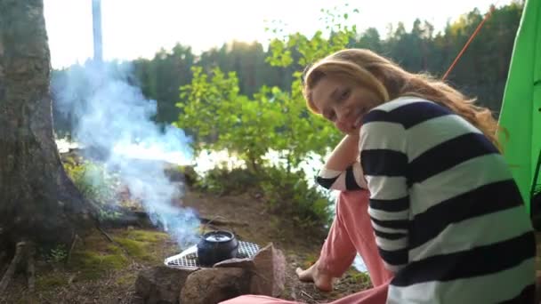 Une jeune femme dans la tente au bord d'un lac forestier — Video