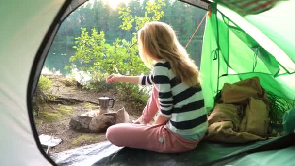 Een jonge vrouw in de tent aan de oever van een bosmeer — Stockvideo