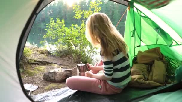 Una joven en la tienda de campaña en la orilla de un lago del bosque — Vídeos de Stock