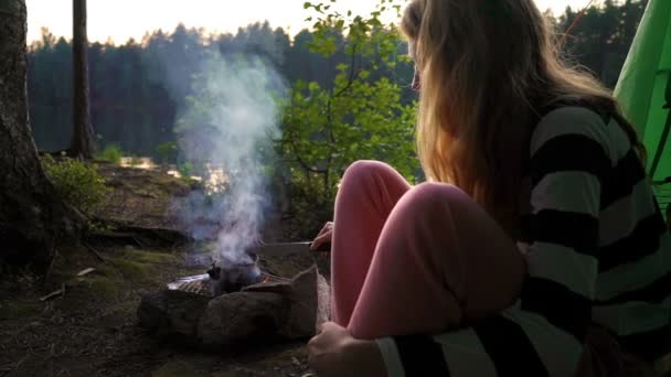 Une jeune femme dans la tente au bord d'un lac forestier — Video