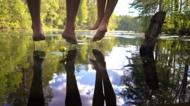 Young couple enjoying silence by the forest lake sitting on the edge of a wooden jetty — Stock Video