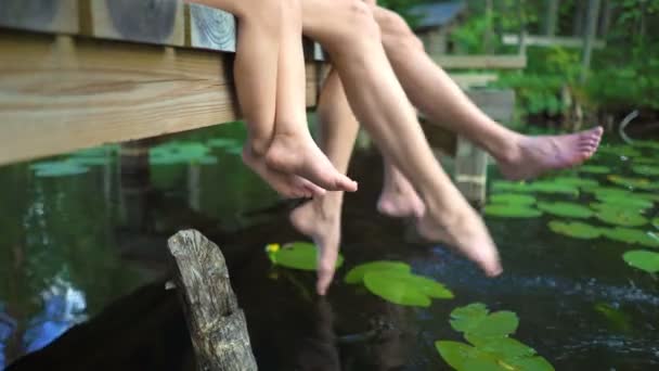 Young couple with child sitting on the edge of a wooden jetty — Stock Video