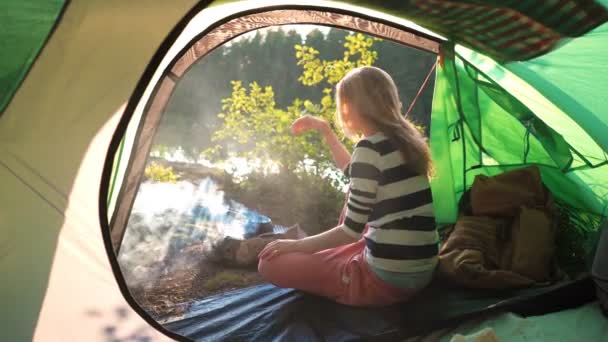 Młoda kobieta w namiocie na brzegu leśnego jeziora — Wideo stockowe