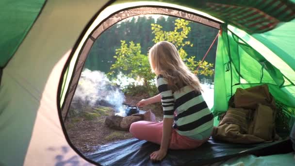 Młoda kobieta w namiocie na brzegu leśnego jeziora — Wideo stockowe