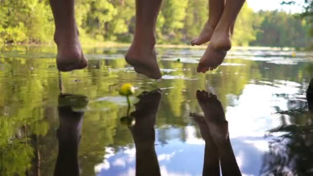 Young couple enjoying silence by the forest lake sitting on the edge of a wooden jetty — Stock Video