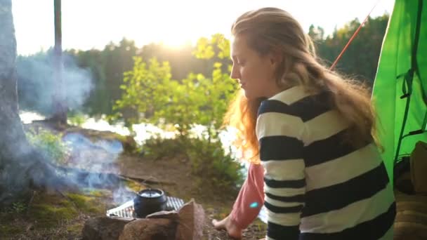 Une jeune femme dans la tente au bord d'un lac forestier — Video