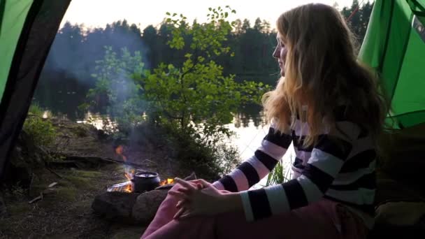 Uma jovem mulher na tenda na margem de um lago florestal — Vídeo de Stock