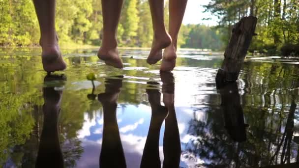 Jovem casal desfrutando de silêncio junto ao lago da floresta sentado à beira de um molhe de madeira — Vídeo de Stock