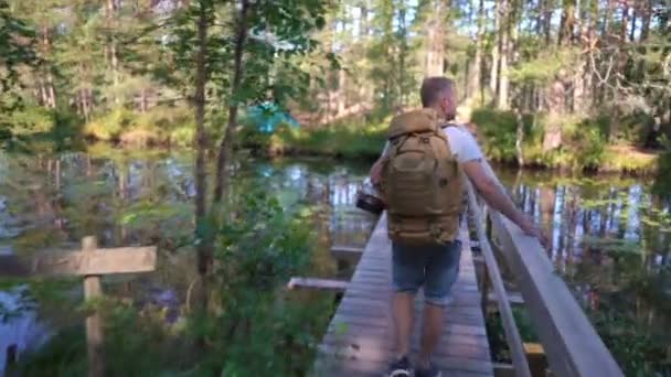 Een man met een grote rugzak wandelend over een toeristisch bospad — Stockvideo