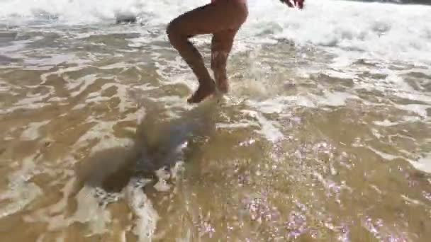 Menina feliz vestindo maiô rosa pulando e brincando com ver ondas na praia — Vídeo de Stock