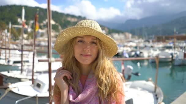 Retrato de mujer joven con sombrero de paja sonriendo a la cámara con fondo de mar . — Vídeo de stock