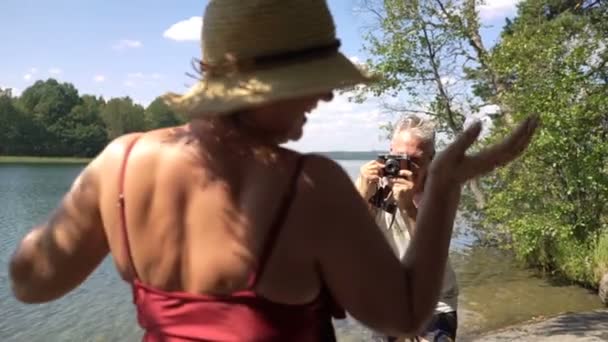 Älterer Mann fotografiert attraktive Seniorin mit Oldtimer-Kamera am Strand. — Stockvideo