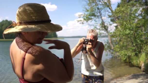 Älterer Mann fotografiert attraktive Seniorin mit Oldtimer-Kamera am Strand. — Stockvideo