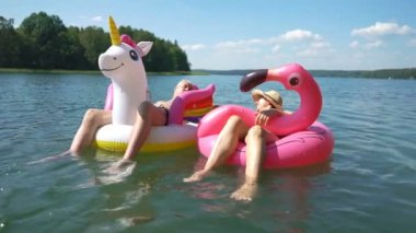 Şişme flamingo ve tek boynuzlu at üzerinde yüzen yaşlı bir çift..