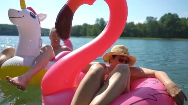 Pareja mayor flotando en flamenco inflable y unicornio . — Vídeos de Stock