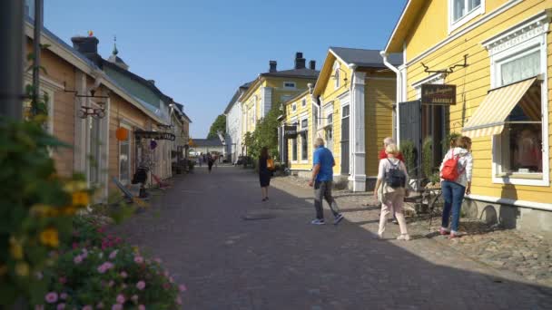 许多游客沿着芬兰波尔沃市中世纪旧城区的鹅卵石街道走过商店. — 图库视频影像