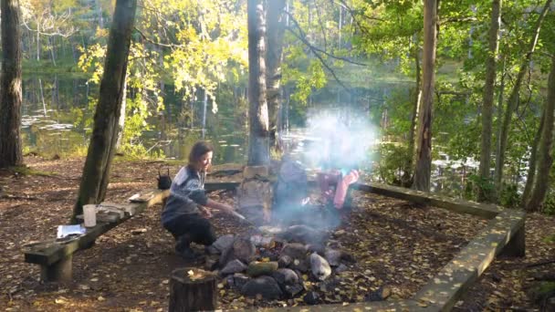 Amigas cocinando panqueques tradicionales sobre una chimenea en el campamento al aire libre durante una caminata — Vídeo de stock